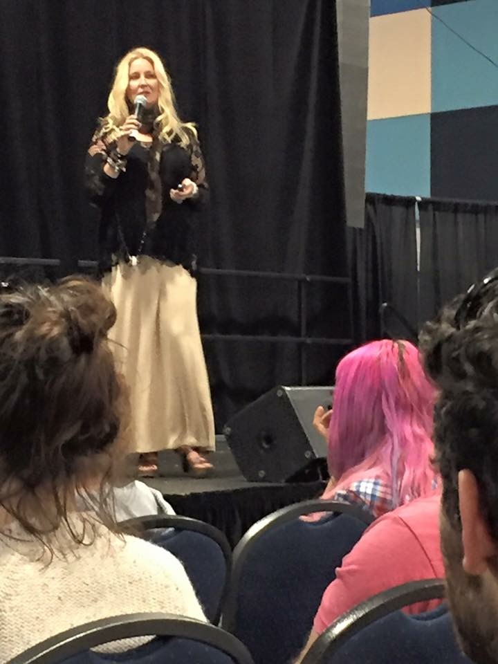 Krista on stage speaking to a seated audience