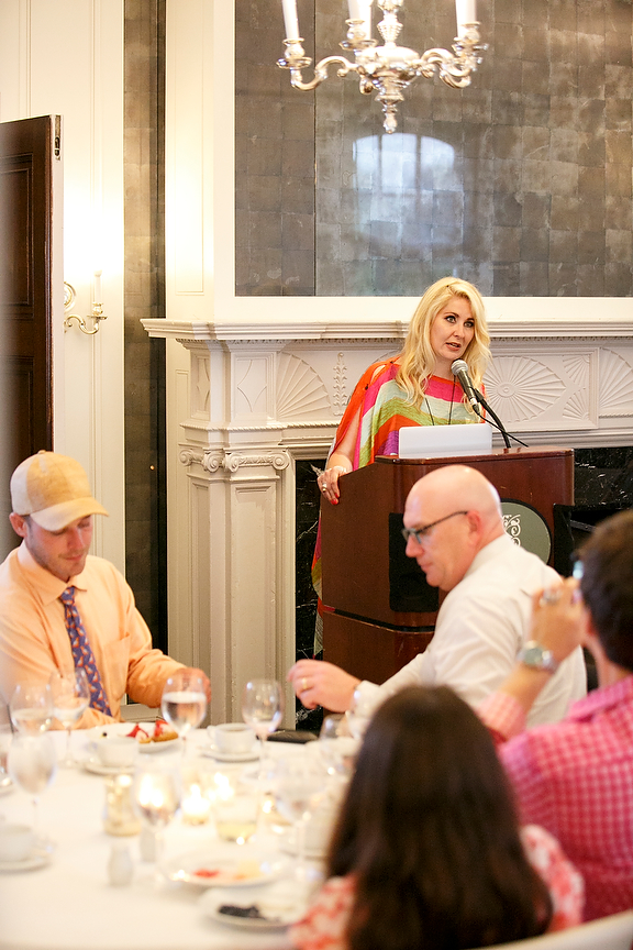 Krista speaking at a podium during a dinner event